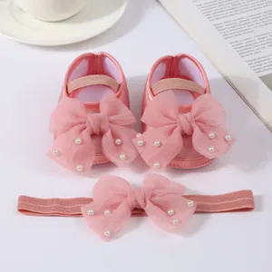 Detailed view of pink baby shoes and headband set with organza bows and pearls.