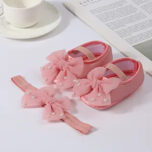 Detailed view of pink baby shoe and headband set decorated with tulle bows and white pearls