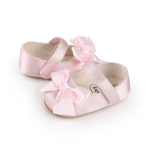 Close-up detail of soft pink satin baby Mary Jane walking shoes with elegant bow decoration