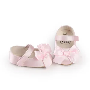 Close-up of pink satin baby walker shoes featuring a large decorative bow