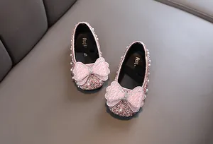 Nahaufnahme von funkelnden rosa Prinzessinnenschuhen für Mädchen mit Perlenbogen.