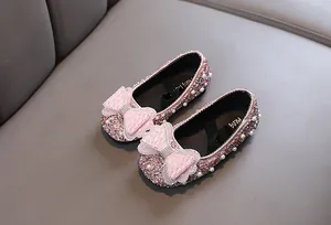 Detailansicht von rosa Glitzer-Prinzessinenschuhen mit großen Schleifen und Perlen.