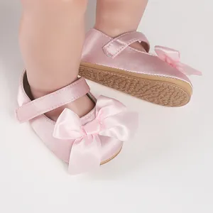 Close-up of pink satin baby walker shoes with decorative bow and non-slip sole
