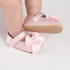 Close-up view of elegant pink satin baby walker shoes featuring a large ribbon bow