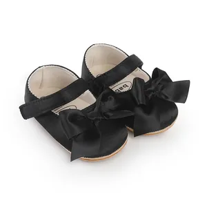 Detailed macro shot of black satin baby walker shoes featuring a large elegant bow