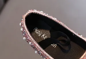 Detailansicht von rosa Mädchen-Prinzessinenschuhen mit Strasssteinen und weißen Perlenverzierungen.