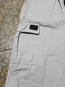 Primo piano della tasca laterale cargo su pantaloncini da uomo grigio chiaro con patch nera.