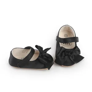 Detailed view of black satin infant Mary Jane walking shoes with large decorative bows