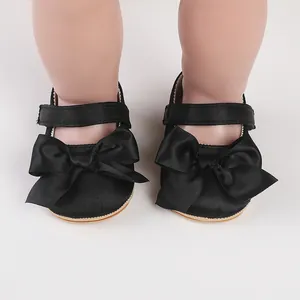 Close-up view of black baby walking shoes featuring an elegant satin bow detail