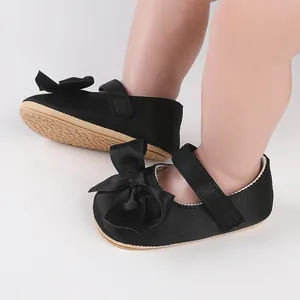 Close-up of elegant black baby walking shoes with decorative bow and velcro strap detail.