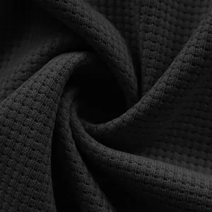 Close-up detail of dark charcoal waffle-knit fabric showing textured weave pattern.