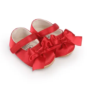 Detailed view of red baby walker shoes with a large decorative satin bow and strap