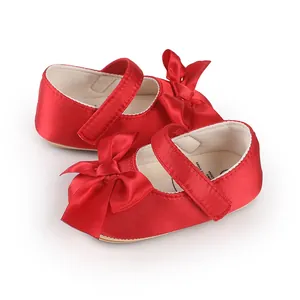 Close-up of red satin baby walker shoes with elegant bow details