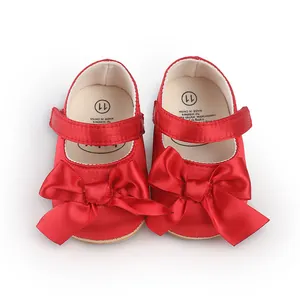 Detail macro view of vibrant red baby pre-walker shoes featuring oversized satin bows