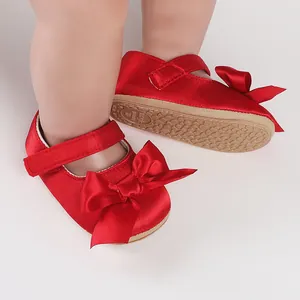 Detailed view of red satin baby walking shoes with ribbon bow and soft non-slip sole