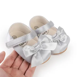 Detailed view of silver satin baby pre-walker shoes with a decorative large bow
