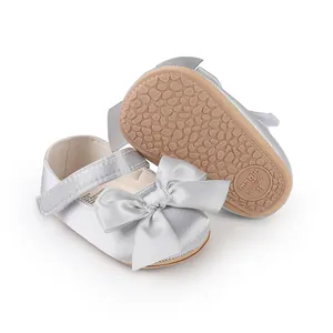Detail showing silver baby walking shoes with silk bow and anti-slip sole.