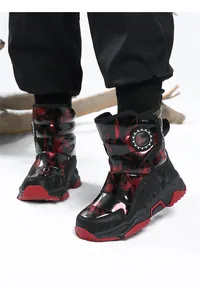 Detail shot of kids red and black flame pattern snow boots on white snow surface