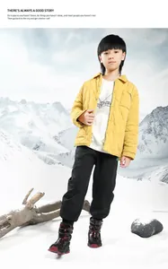 Detail view of children's thick snow boots worn by a boy in a scenic winter landscape