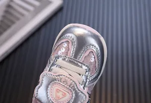 Macro detail of silver microfiber leather toddler shoe with pink mesh inserts
