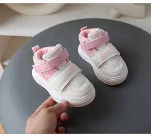 Detail shot of pink and white toddler sneakers with velcro straps and soft soles.