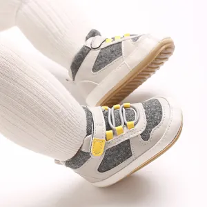 Nahaufnahme von grau-weißen Babyschuhen mit gelben Schlaufen und weicher Gummisohle