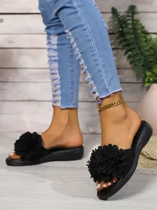 Primo piano di sandali neri da donna con eleganti decorazioni floreali 3D ai piedi