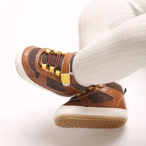 Detailaufnahme von braunen Baby-Lernlaufschuhen für Jungen mit weicher Sohle und gelben Akzenten.
