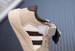 Λεπτομέρεια από μπεζ αγορίστικα αθλητικά παπούτσια με καφέ ρίγες και βέλκρο