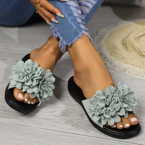 Dettaglio di sandali da donna con grandi decorazioni floreali verde salvia su suole nere