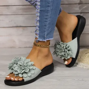 Dettaglio di sandali con zeppa da donna con grande fiore 3D su cinturini grigi