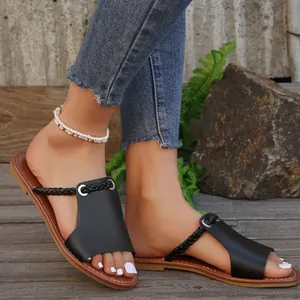 Close-up of black flat sandals with braided strap on model for summer beach wear