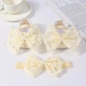 Detail of cream baby shoes and headband set with large lace bows and pearls.