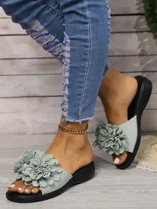 Dettaglio dei sandali con zeppa verde chiaro e decorazione floreale su un denim