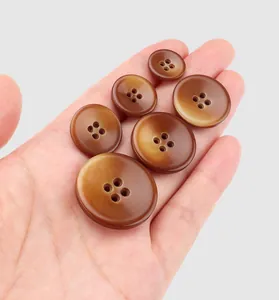 Detailed view of multiple brown resin buttons in various sizes held in a human palm