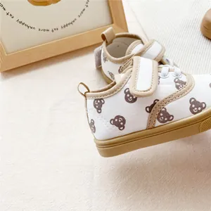 Detail of children's canvas shoes with cute brown bear prints and velcro straps.