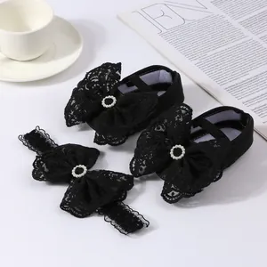 Detail view of black lace bow baby shoes and matching pearl headband set