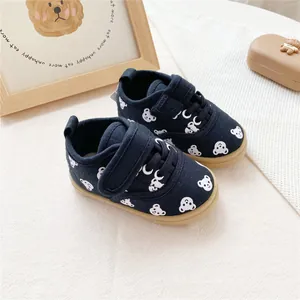 Close-up of navy blue baby canvas shoes featuring white bear print and velcro straps.