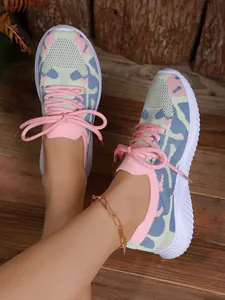 Detalle de zapatillas de punto para mujer con estampado camuflaje pastel y suela blanca gruesa.