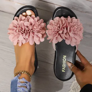 Vista dettagliata di un grande fiore in tessuto rosa su sandali platform neri da donna dorati