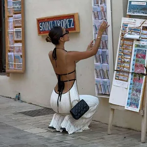 Model wearing a white backless halter knit dress in a Mediterranean street setting