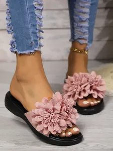 Primo piano di sandali a fiori rosa con suola a zeppa ai piedi della modella.