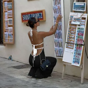 Model wearing a black backless halter knitted dress in a chic outdoor street setting.