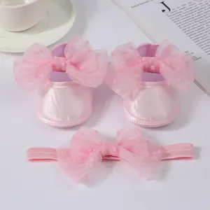 Primer plano de zapatos de princesa rosas para bebé y conjunto de diadema con lazo