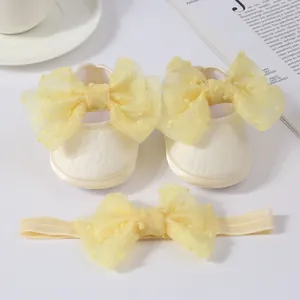 Vista detallada del conjunto de zapatos para bebé crema y diadema con lazos amarillos
