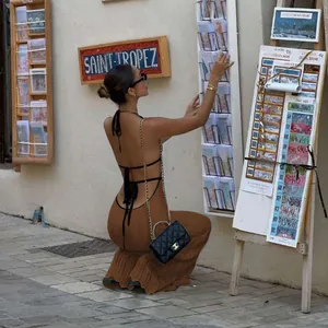 Model wearing a brown knitted halter neck backless maxi dress in an outdoor street setting