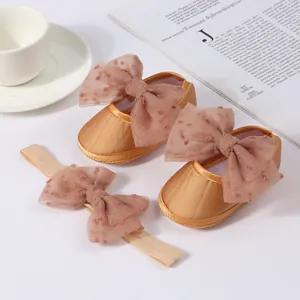 Detalle de los elegantes zapatos de princesa dorados y diadema para bebé set
