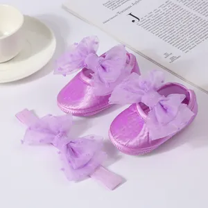 Primer plano de zapatos de princesa morados para bebé con diadema de lazo a juego
