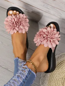 Dettaglio della decorazione floreale in tessuto rosa su sandali platform da donna.