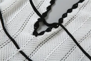 Detailed macro view of the contrast black trim on a white crocheted knitted halter dress